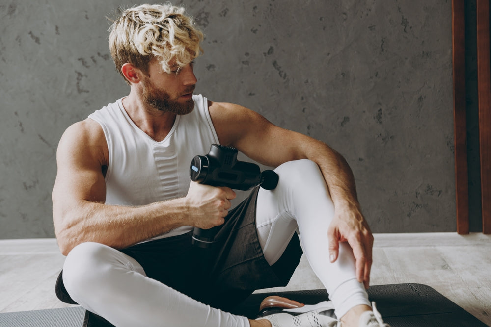 man using a massage gun on his leg