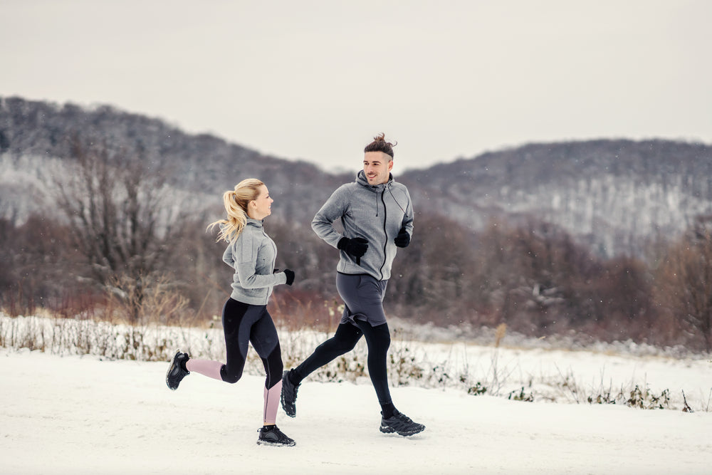 man and woman jogging along snowy path