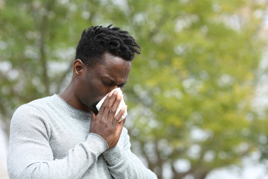 man outside sneezing into a tissue