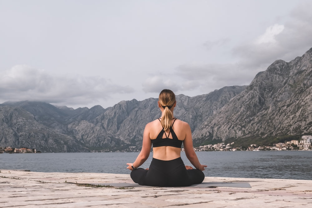 woman practicing yoga with view of lake and mountains