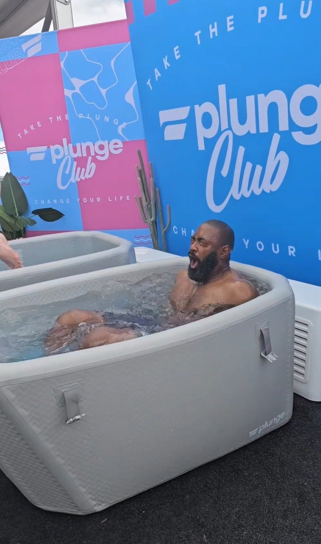 A man experiencing a cold plunge bath in a promotional setup by Plunge Club.