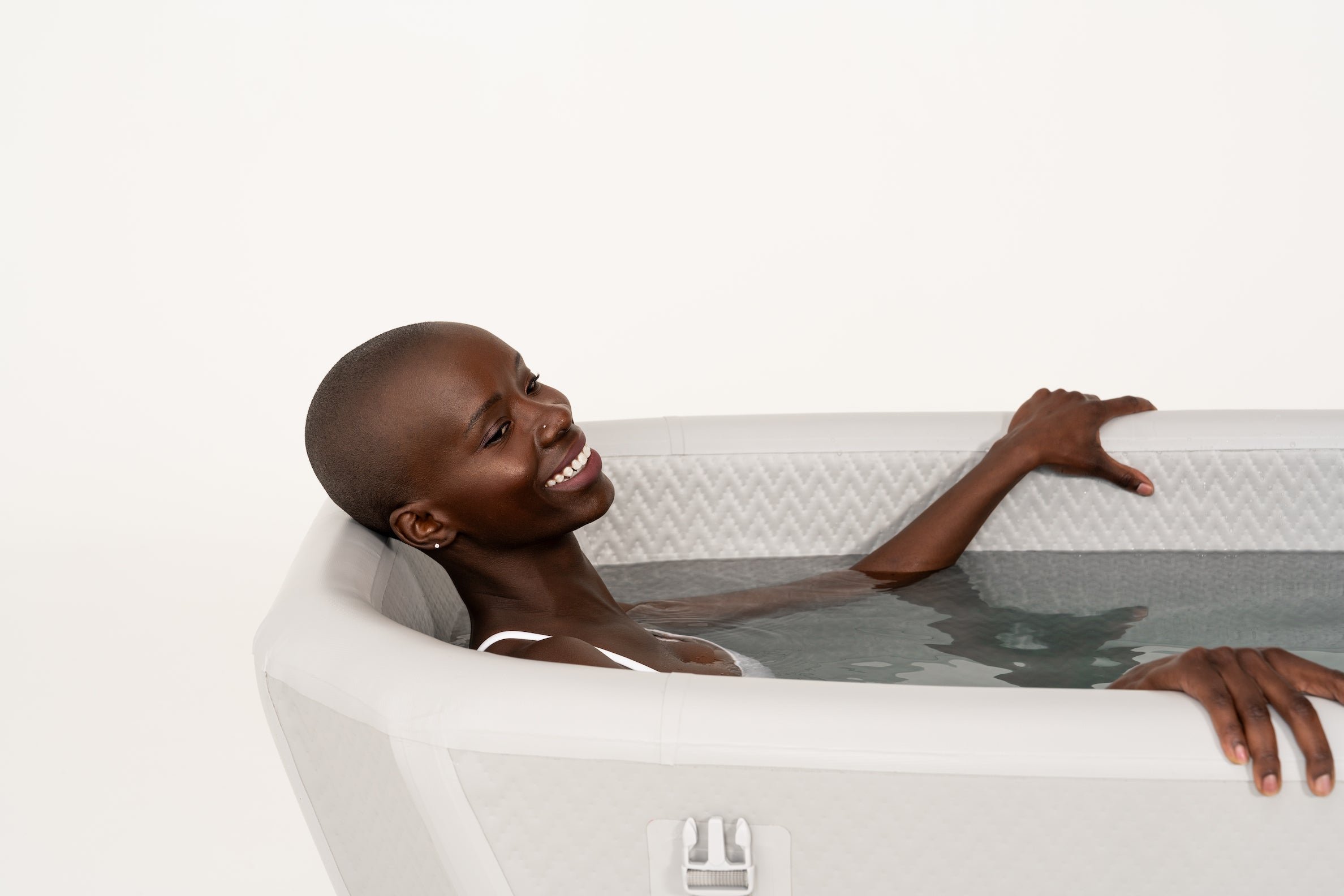 Person smiling and relaxing in a bathtub filled with water.