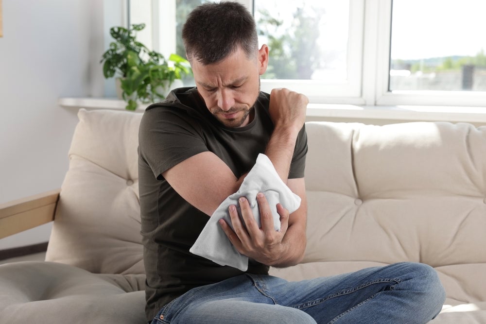 man holding heating pad on his elbow