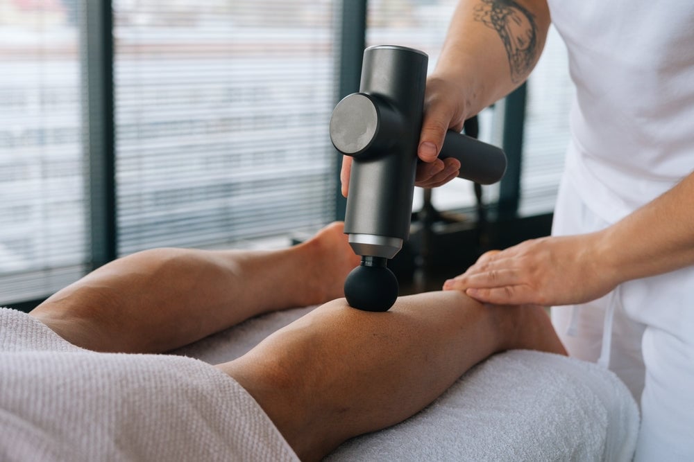 using massage gun on person's calf