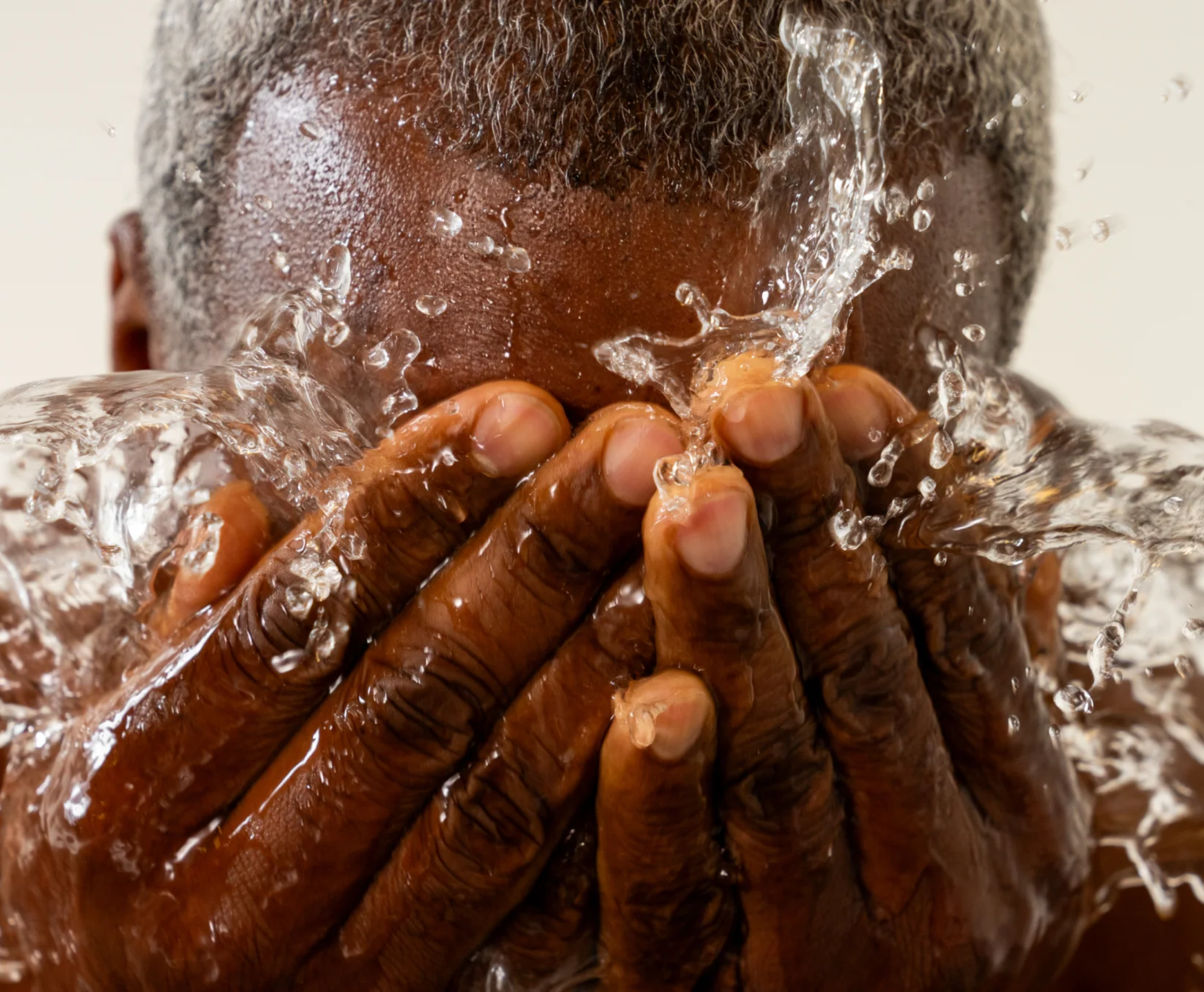 Person washing their face with splashing water.