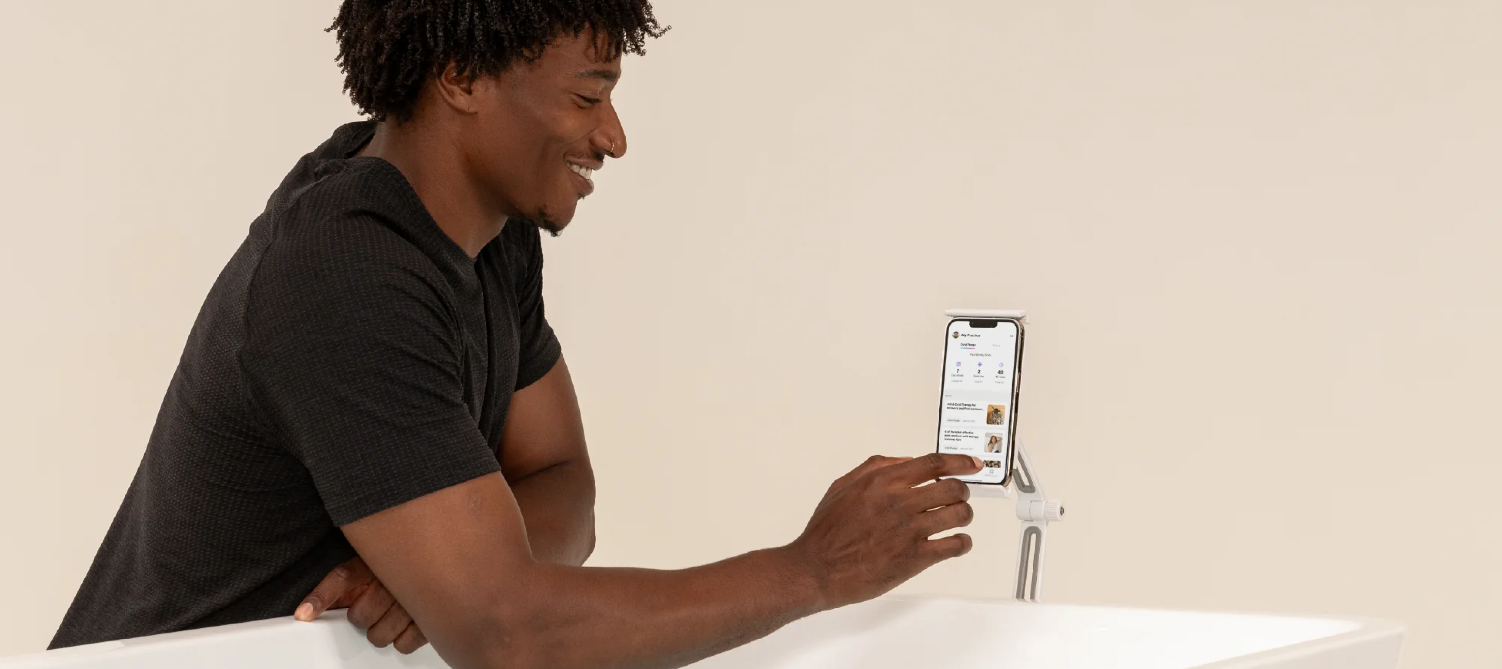 Person smiling and using a smartphone mounted on a stand.