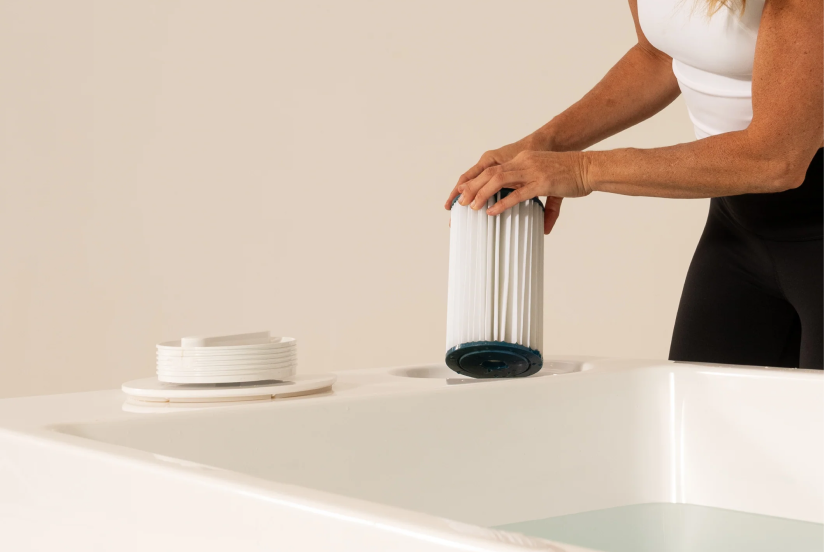 Person replacing a filter in a white bath or hot tub.